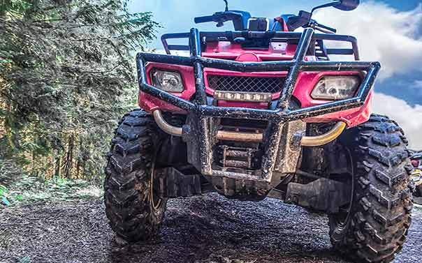 A off-road ATV covered in mud in the forest